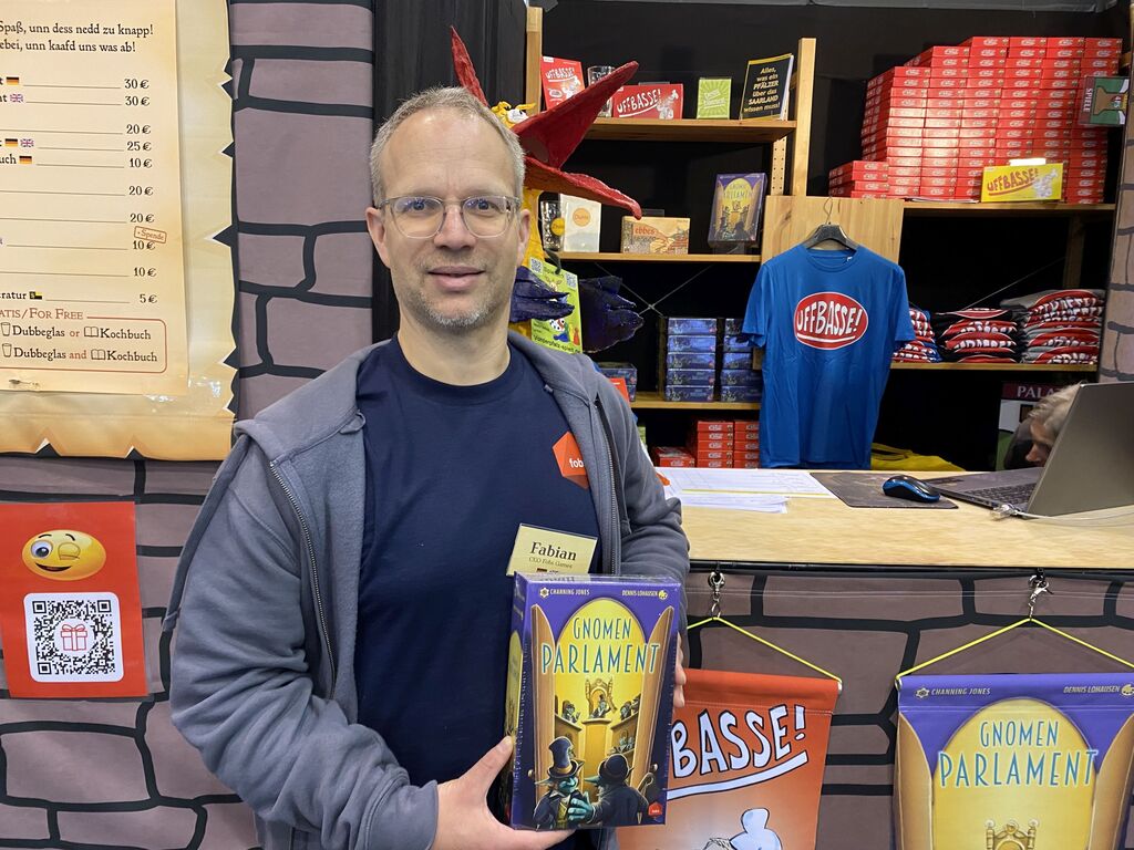 Ein Mann hält ein Spiel vor einem Messestand.