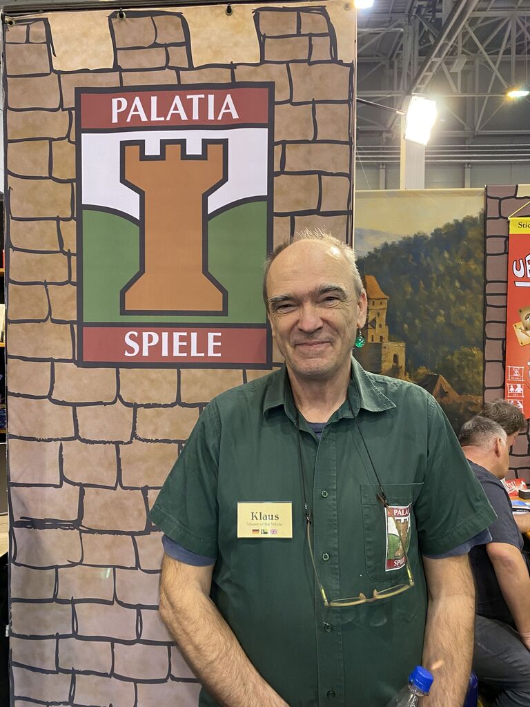 Mann vor Werbewand mit Logo von "Palatia Spiele".