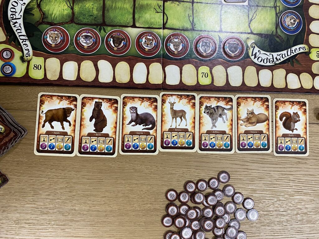 Sieben braune Karten mit Tieren und Symbolen an einem Spielfeldrand.