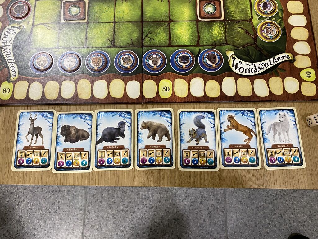 Sieben blaue Karten mit Tieren und Symbolen an einem Spielfeldrand.