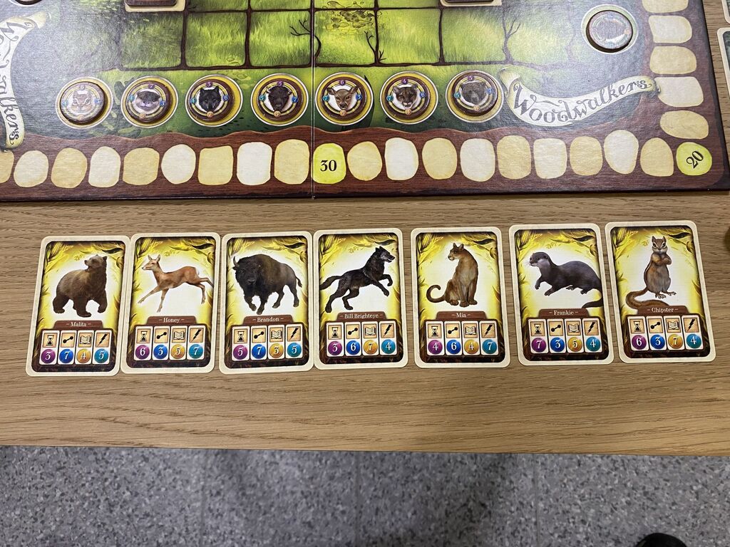 Sieben gelbe Karten mit Tieren und Symbolen an einem Spielfeldrand.