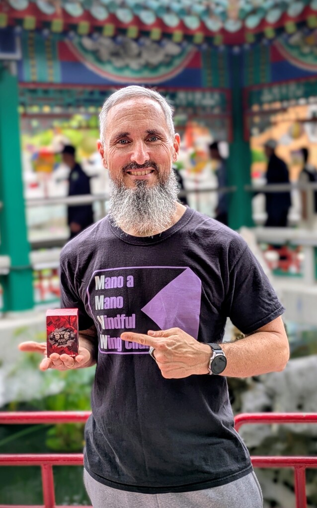 Ein Mann hält ein Spiel in der Hand und zeigt mit der anderen darauf.