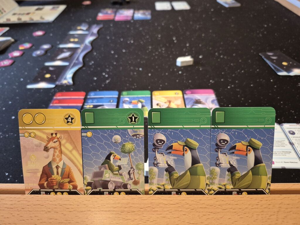 Karten, im Hintergrund weiteres Spielmaterial.