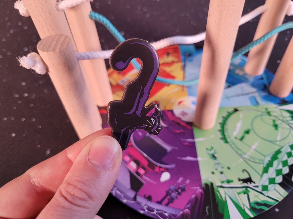 Eine Hand hält ein Katzenplättchen mit gebogenem Schwanz.