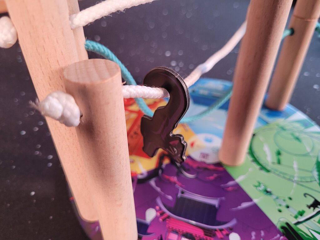 Katzenplättchen hängt an Kabel zwischen zwei Holzsäulen.