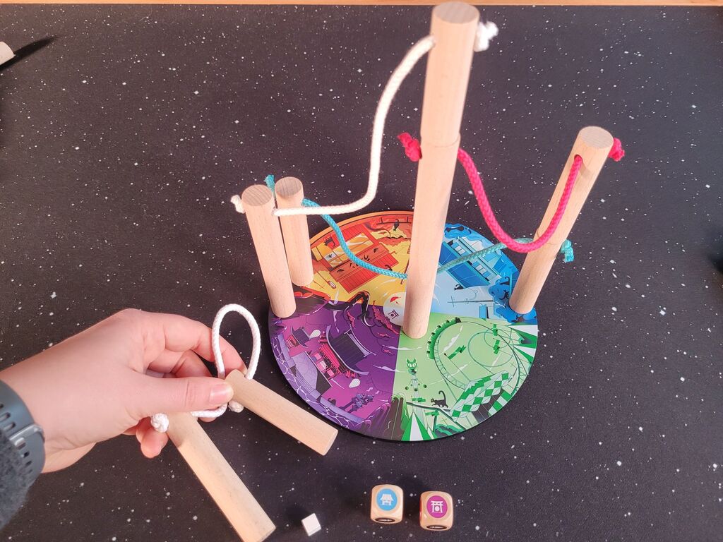 Hand hält Säulen neben Spielmaterial.