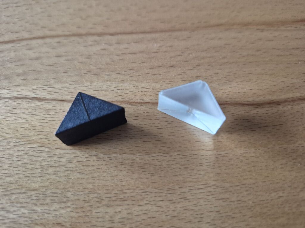 Ein milchig-durchsichtiges und ein schwarzes Dreieck aus "Orapa".