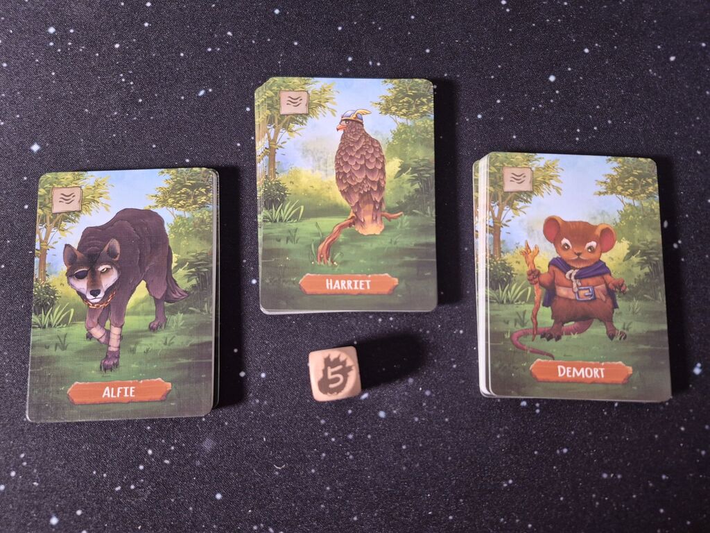 Drei Kartenstapel und ein Würfel.