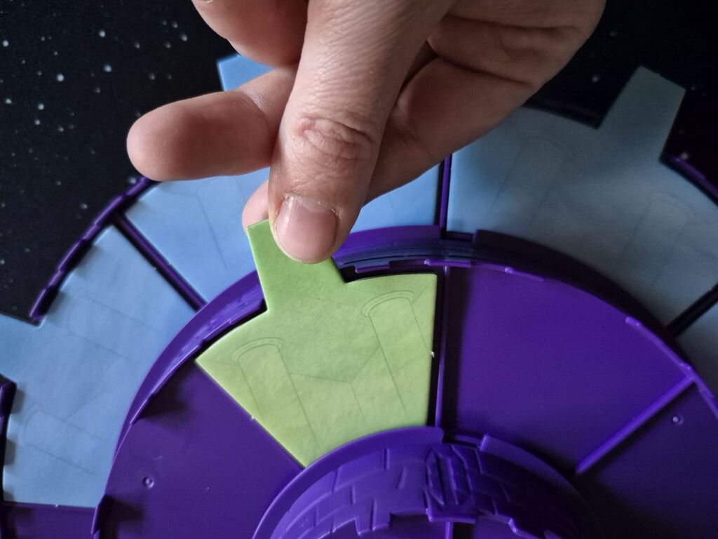 Eine Hand hält ein Teil über den Spielplanaufbau.