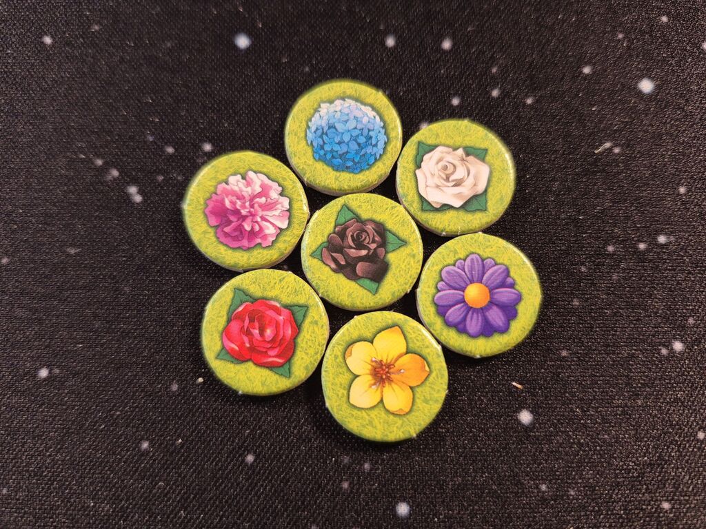 Sieben runde Plättchen mit unterschiedlich gefärbten Blumen.