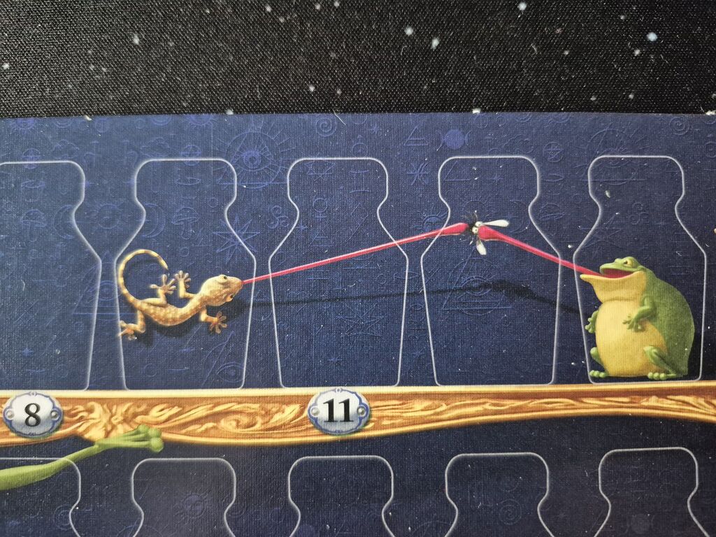 Spielplanausschnitt mit Kröte und Echse, die Fliege fangen wollen.