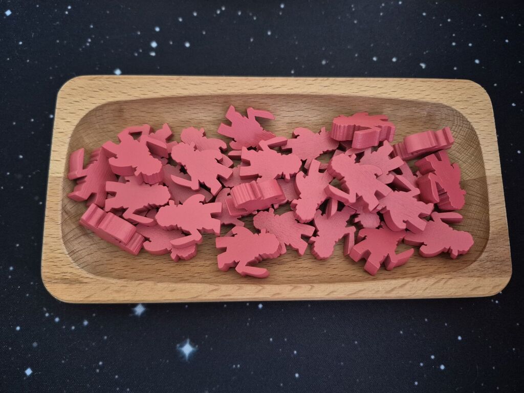 Rote Spielfiguren aus Holz in einer Schale.