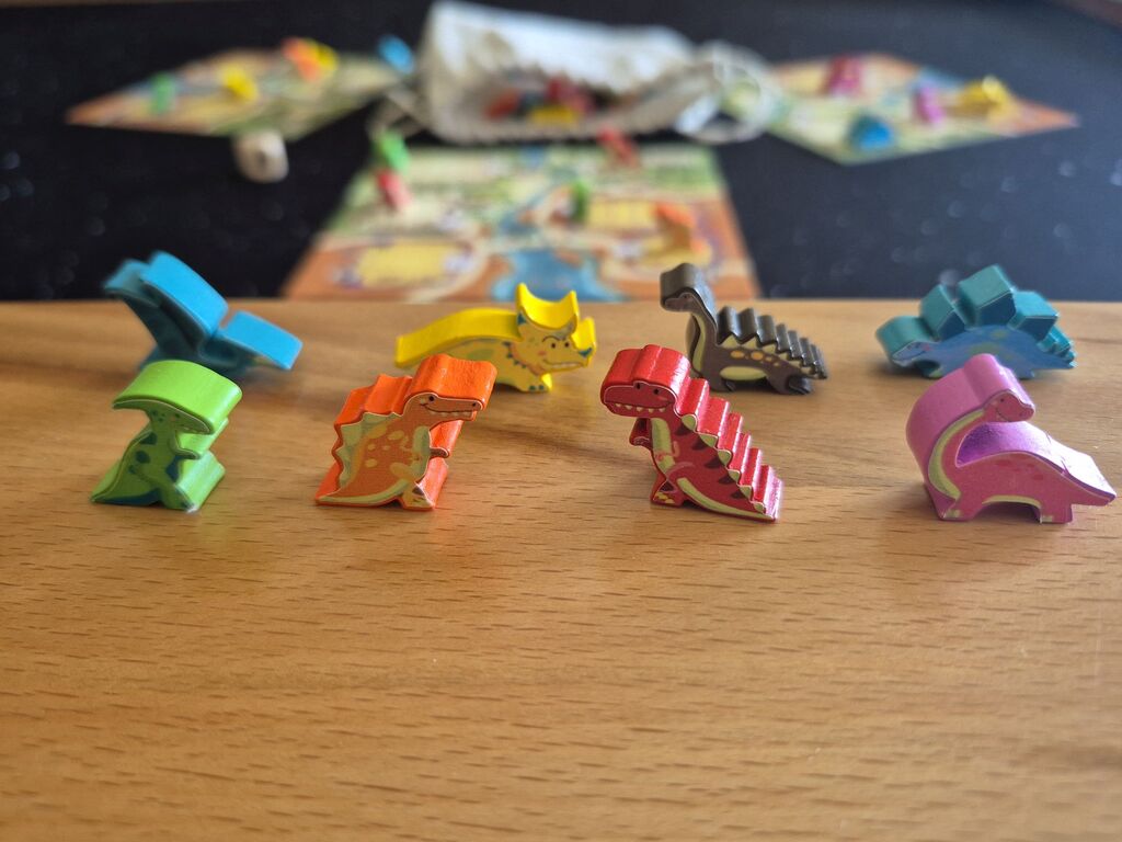 Acht Dinofiguren, im Hintergrund Spielmaterial.