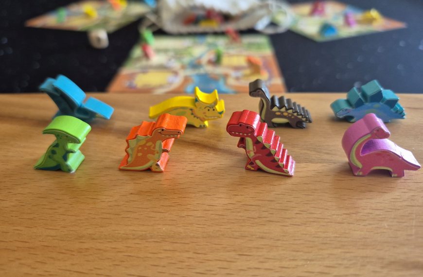 Acht Dinofiguren, im Hintergrund Spielmaterial.