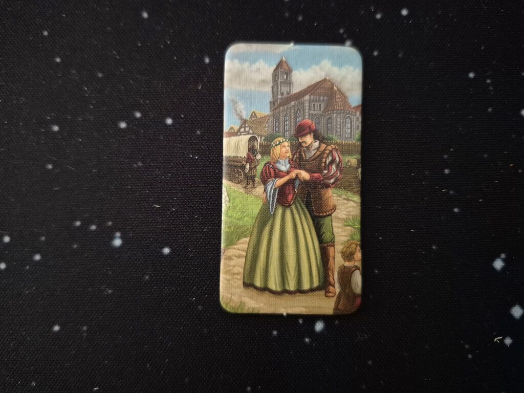 Plättchen mit Paar vor mittelalterlicher Stadt und Planwagen.