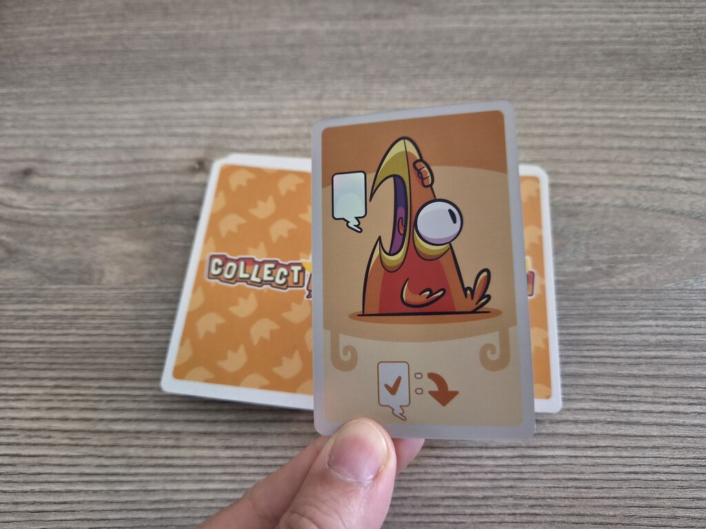 Hand hält Karte mit Comic-Papagei aus "Collect!":