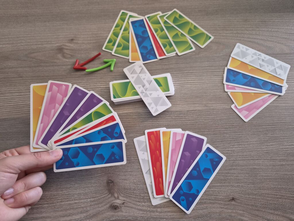 Eine Hand hält Karten, auf dem Tisch mehr Karten.