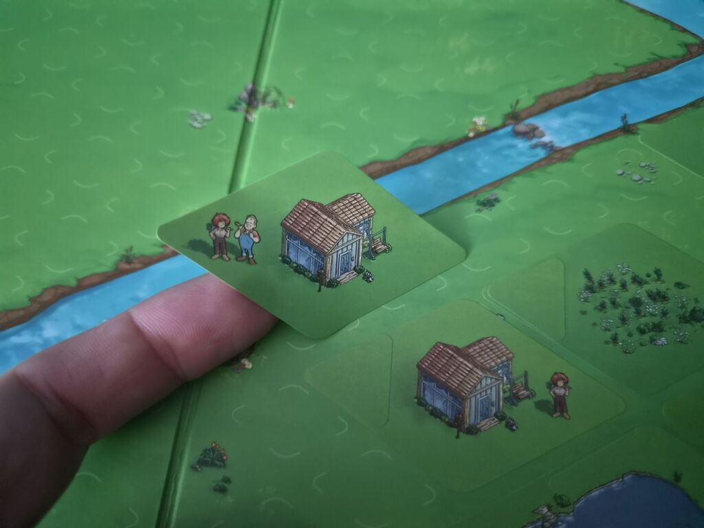 Finger hält Aufkleber über Spielplan.