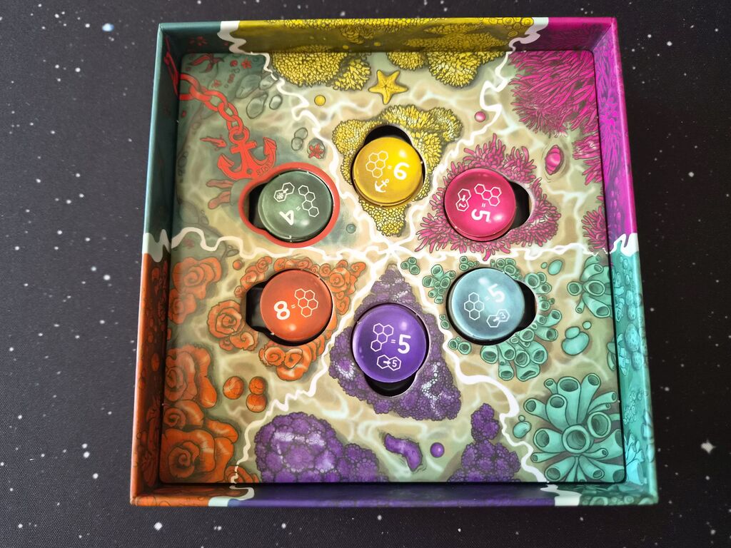 Spielschachtel mit Spielplan und runden Markern.
