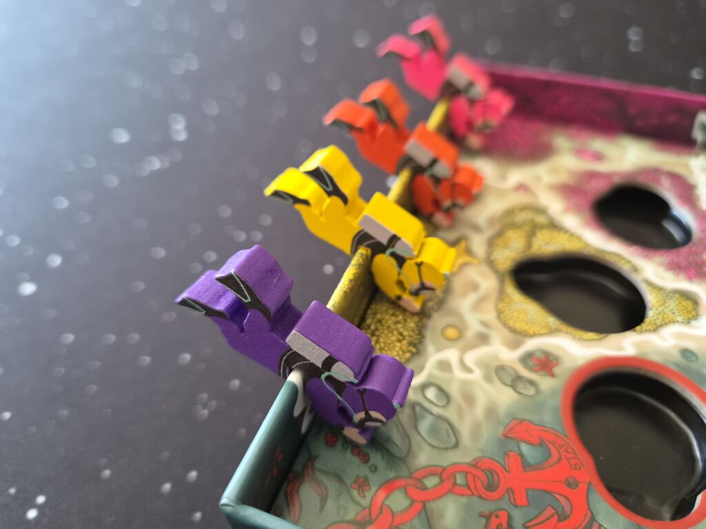 Spielfiguren hängen am Rand der Spielschachtel.
