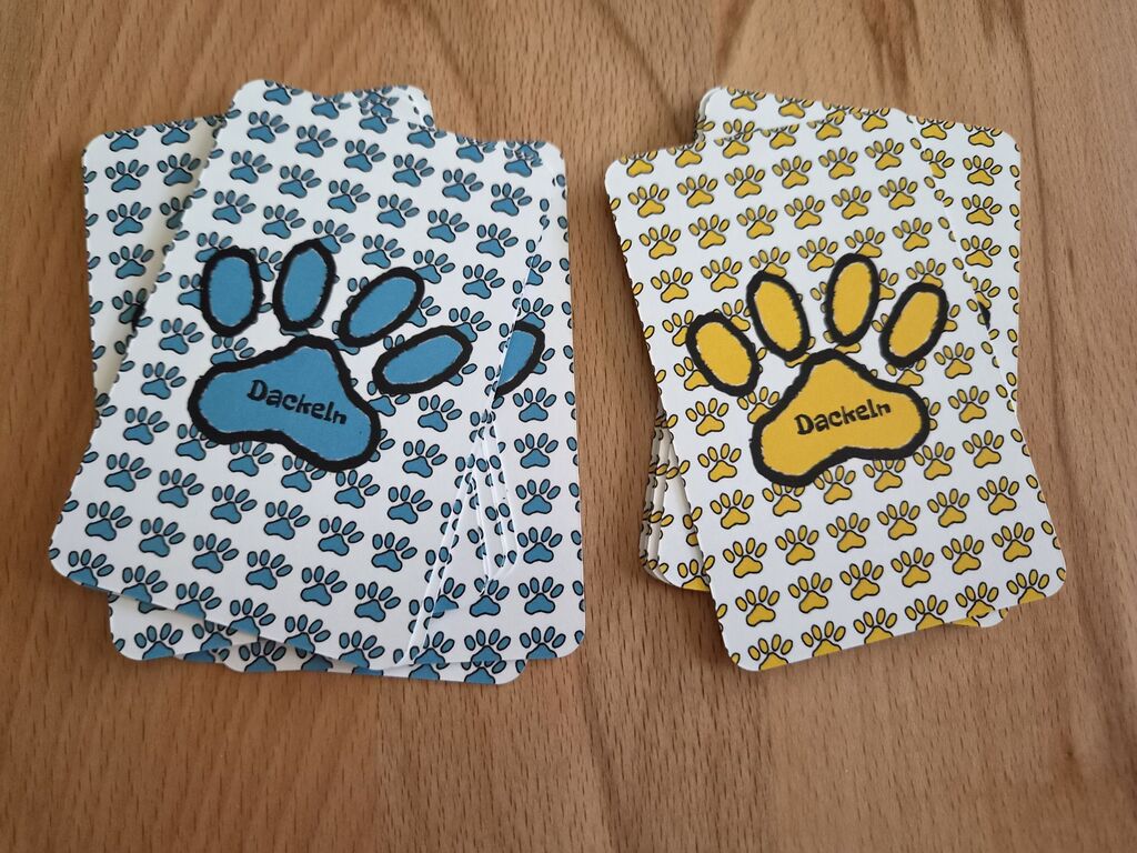 Zwei Kartenstapel mit gelben oder blauen Pfotenabdrücken.
