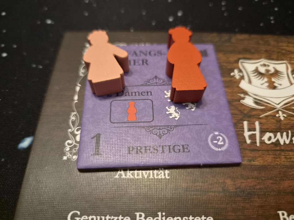 Zwei Spielfiguren auf einem Plättchen aus "Obsession – Upstairs, Downstairs".