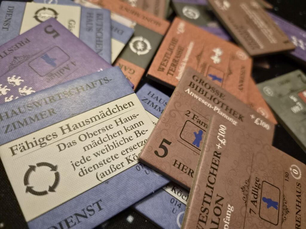 Plättchen mit Text und Symbolen aus "Obsession – Upstairs, Downstairs".