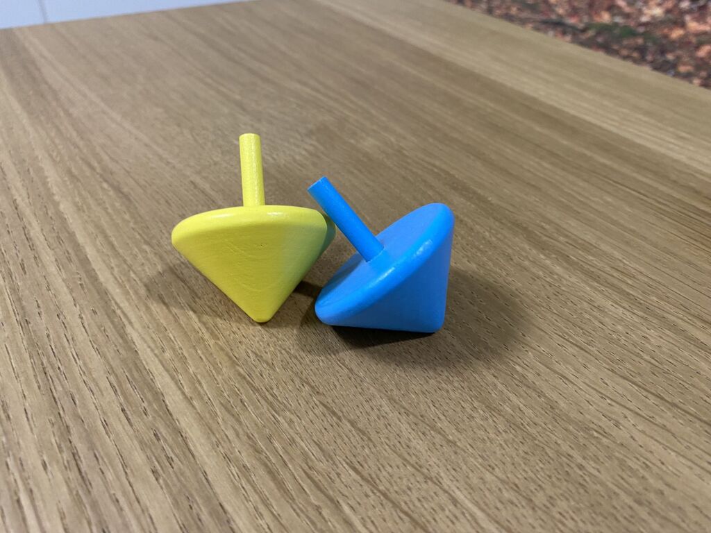 Ein blauer und ein gelber Holzkreisel aus "Task Team".
