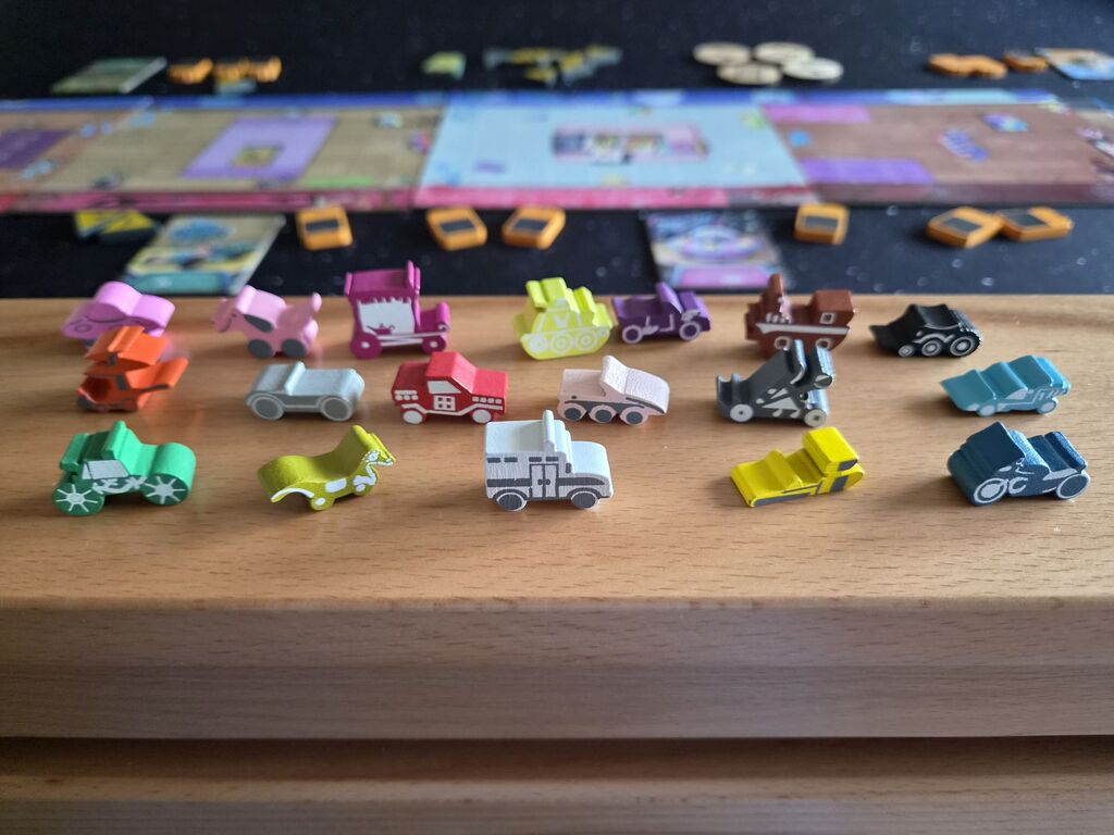 18 Holzfahrzeugmarker, im Hintergrund das Spielmaterial.
