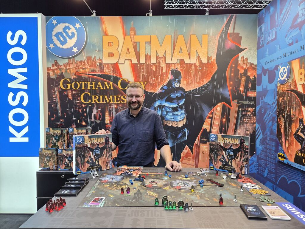 Mann an Messestand vor Batman-Comic-Wand.