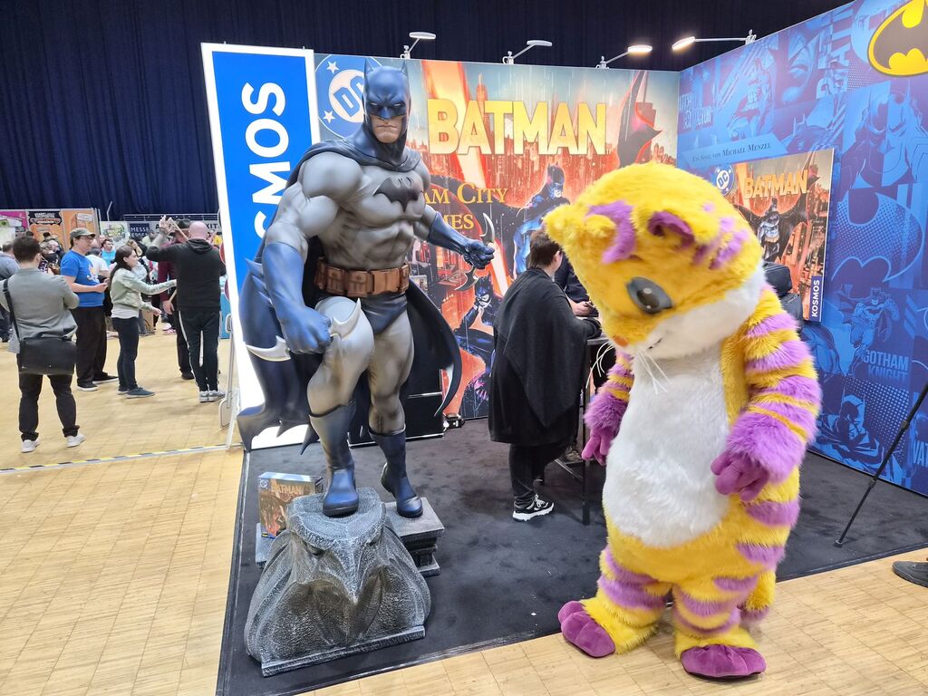 Mensch in Katzenkostüm steht vor großer Batmanfigur.