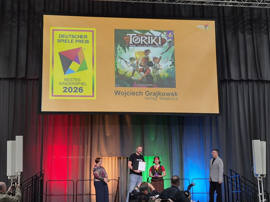 Menschen mit Pokal und Urkunde unter Präsentationsbildschirm mit Spielcover.