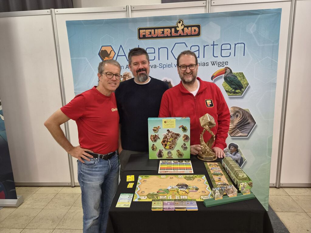 Drei Männer hinter Tisch mit Spiel.