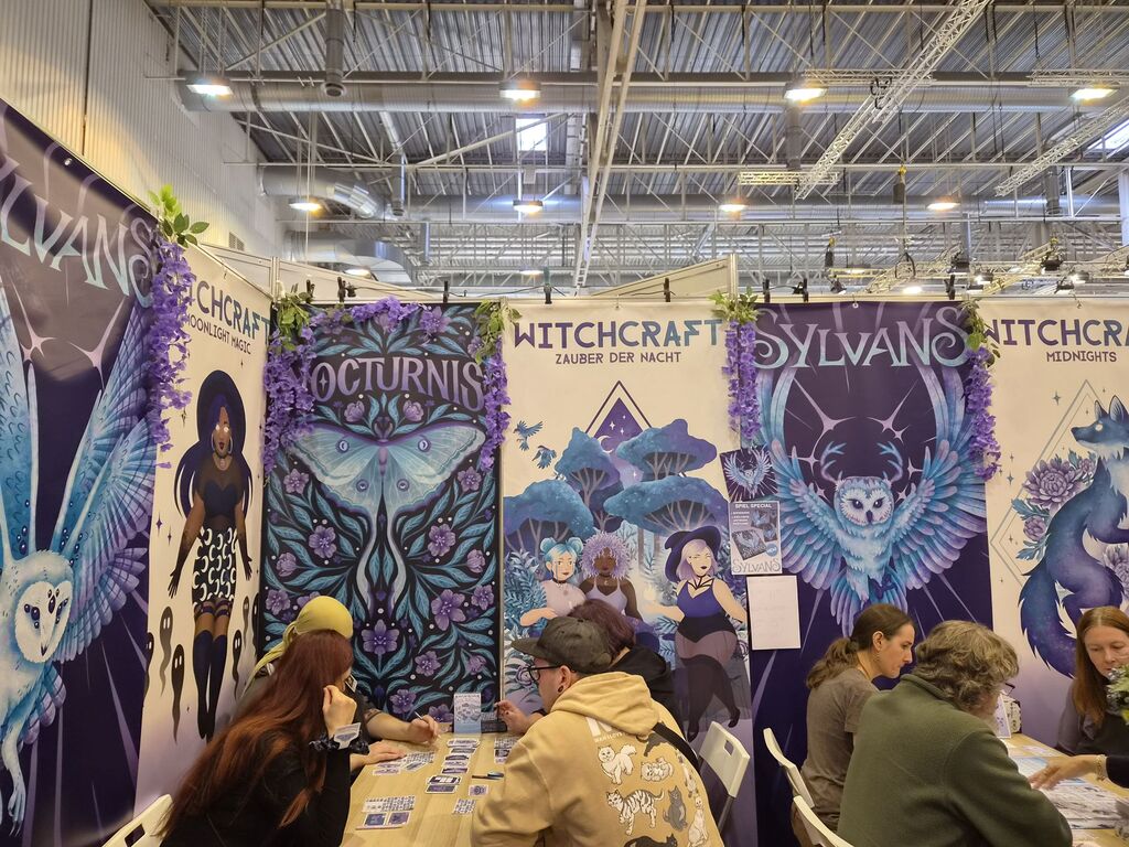 Messestand mit verschiedenen Spielen in Lila- und Türkis-Tönen.