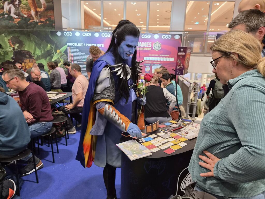 Blau geschminkter Mann in Cosplay-Outfit erklärt Spiel.