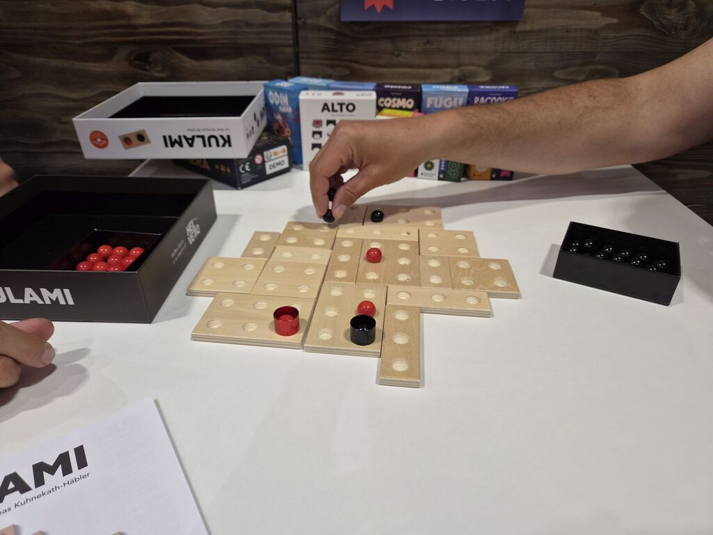 Hand legt Murmel auf Spielplan.
