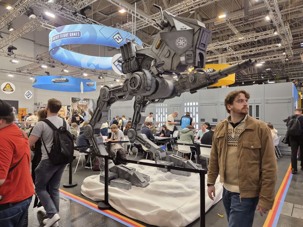 Großer Roboter an Messestand, Mann blickt in gleiche Richtung wie Mündungsrohr.