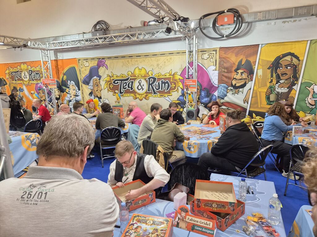 Messestand mit Menschen an Tischen mit Spiel.